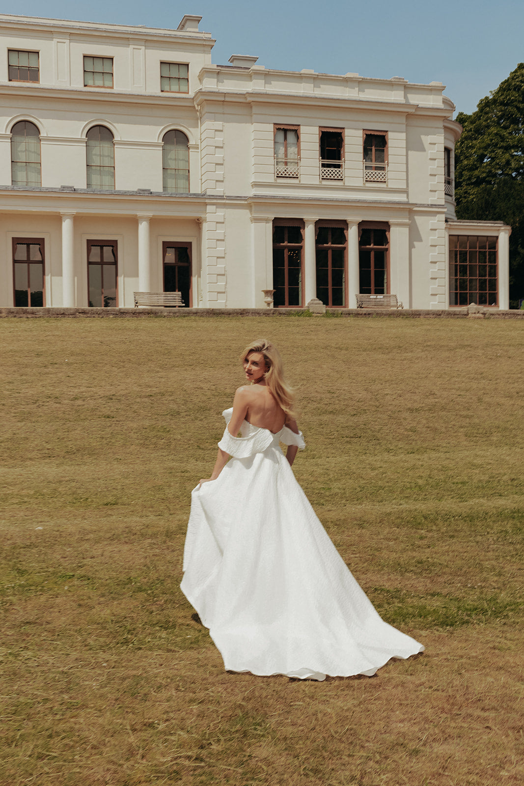 Woman in a ivory wedding dress standing in front of a large building with columns.