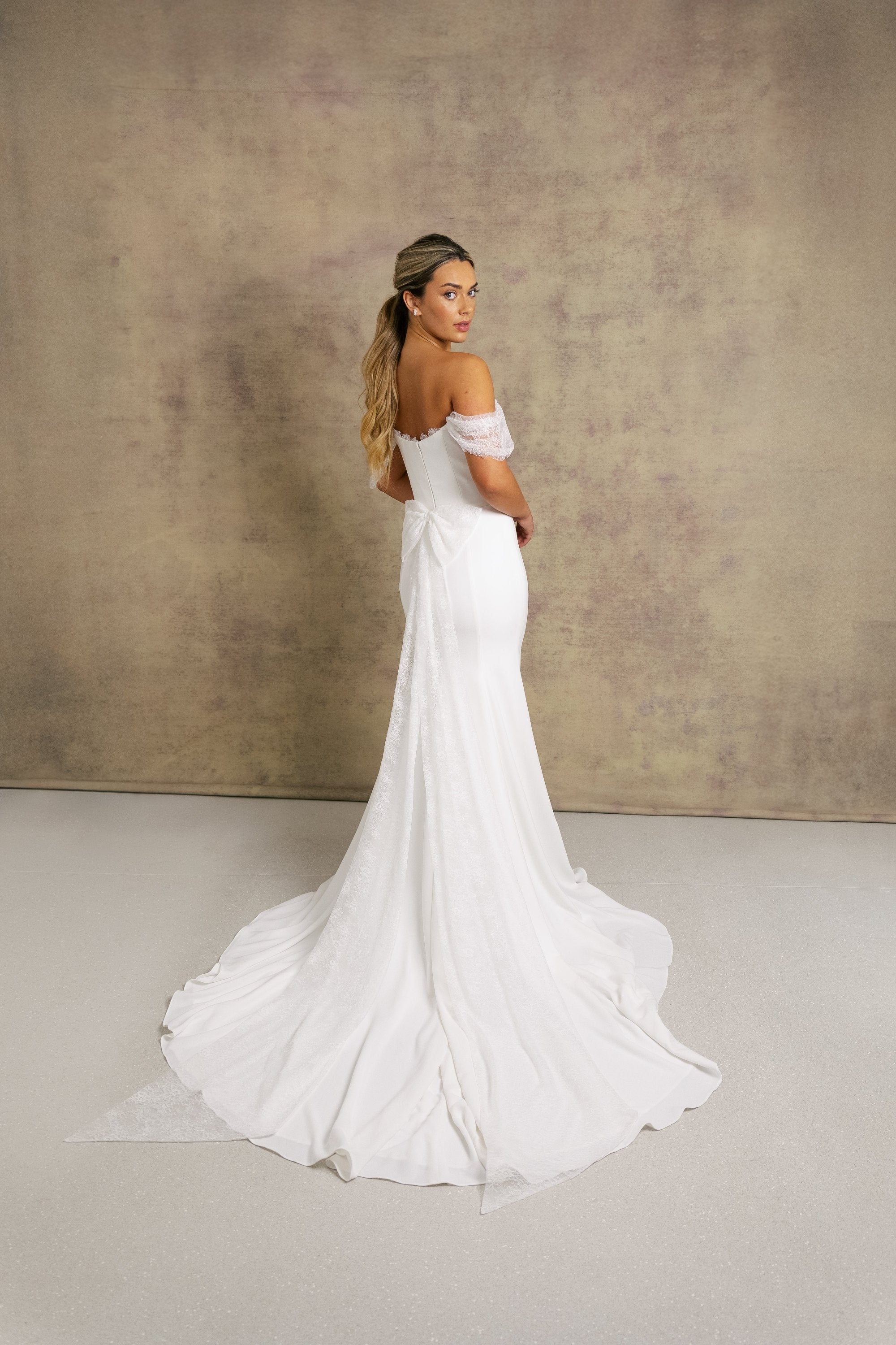A woman in an elegant ivory strapless wedding dress with chantilly lace sleeves and a corseted bodice.