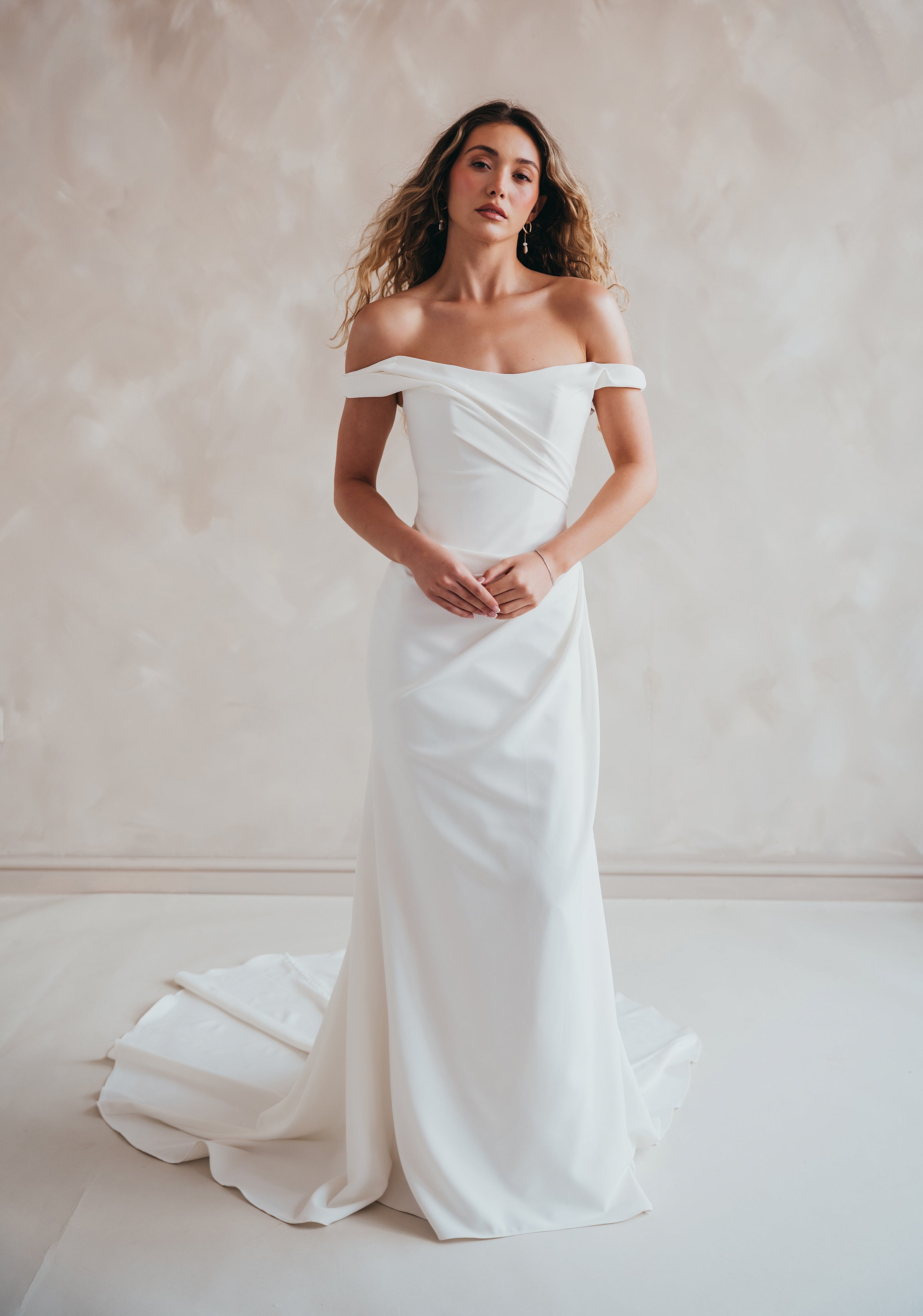 Bride wearing the Hadley off-the-shoulder stretch crepe wedding dress with draped neckline and button-back detail.