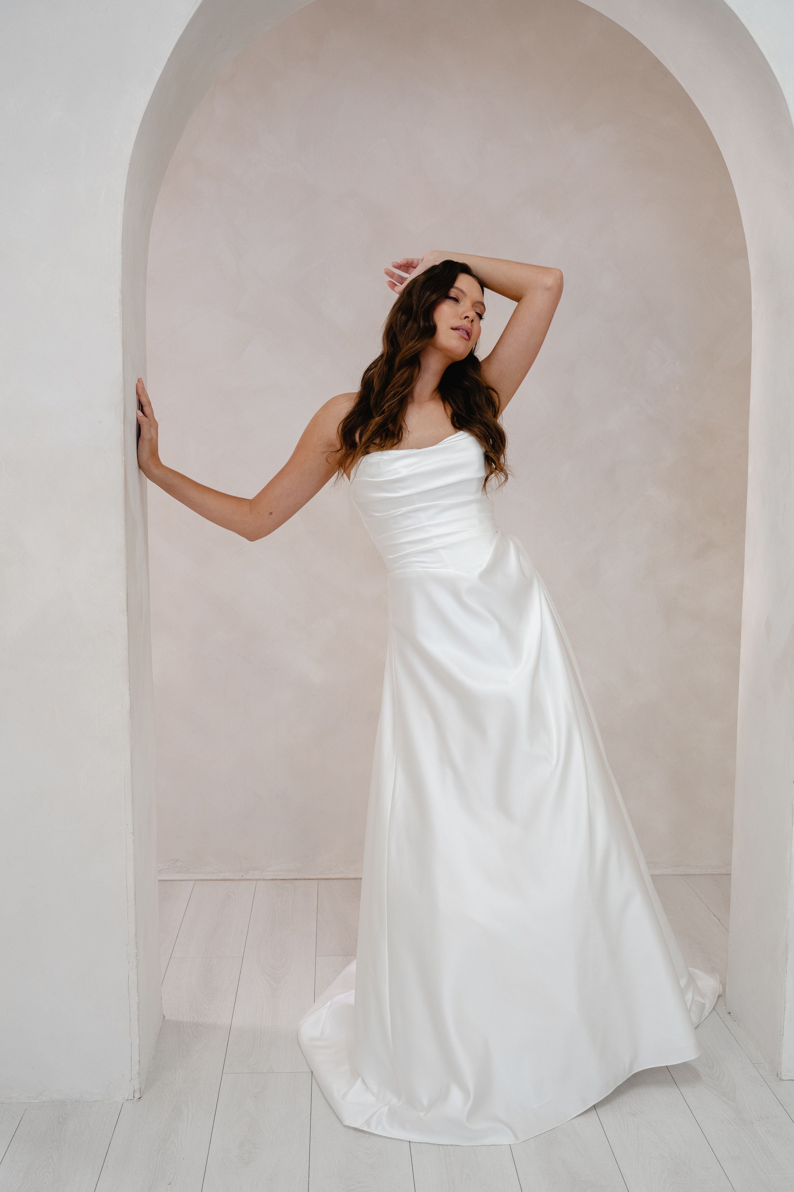 Woman in a white wedding dress standing in an archway.