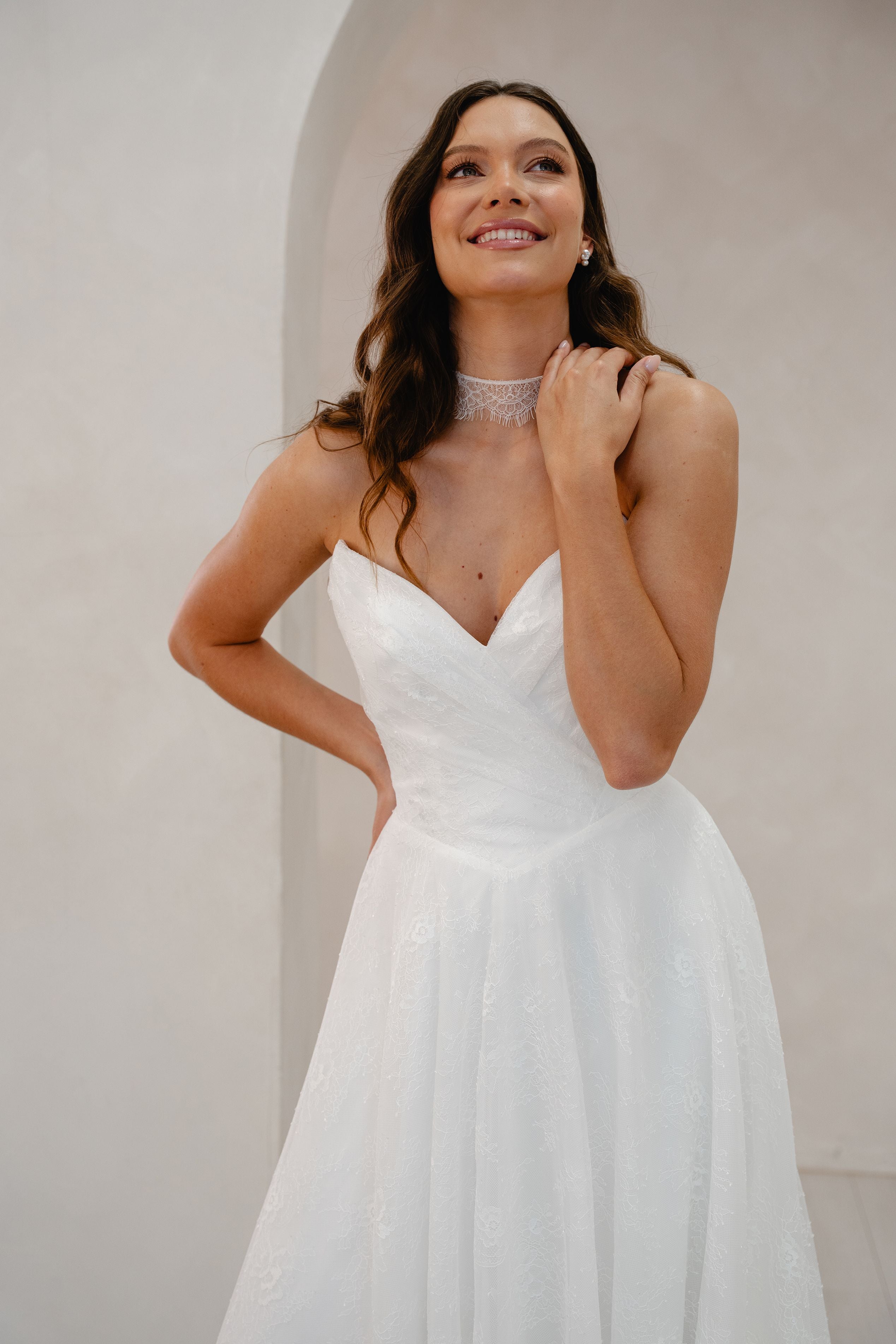 Woman wearing a white wedding dress against a plain background