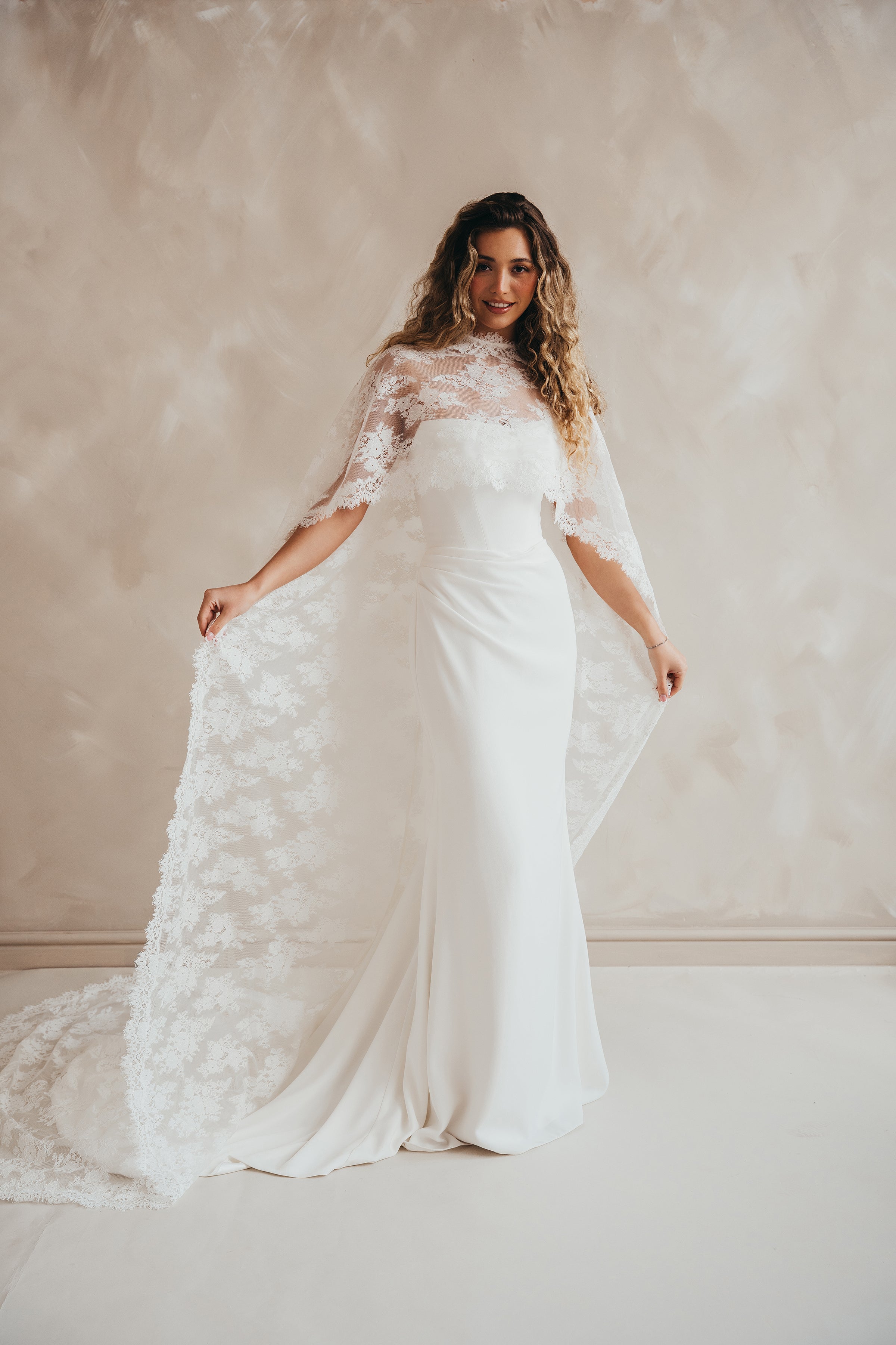 Bride wearing the Lace Roxie bridal cape with high neckline and intricate lace detail.