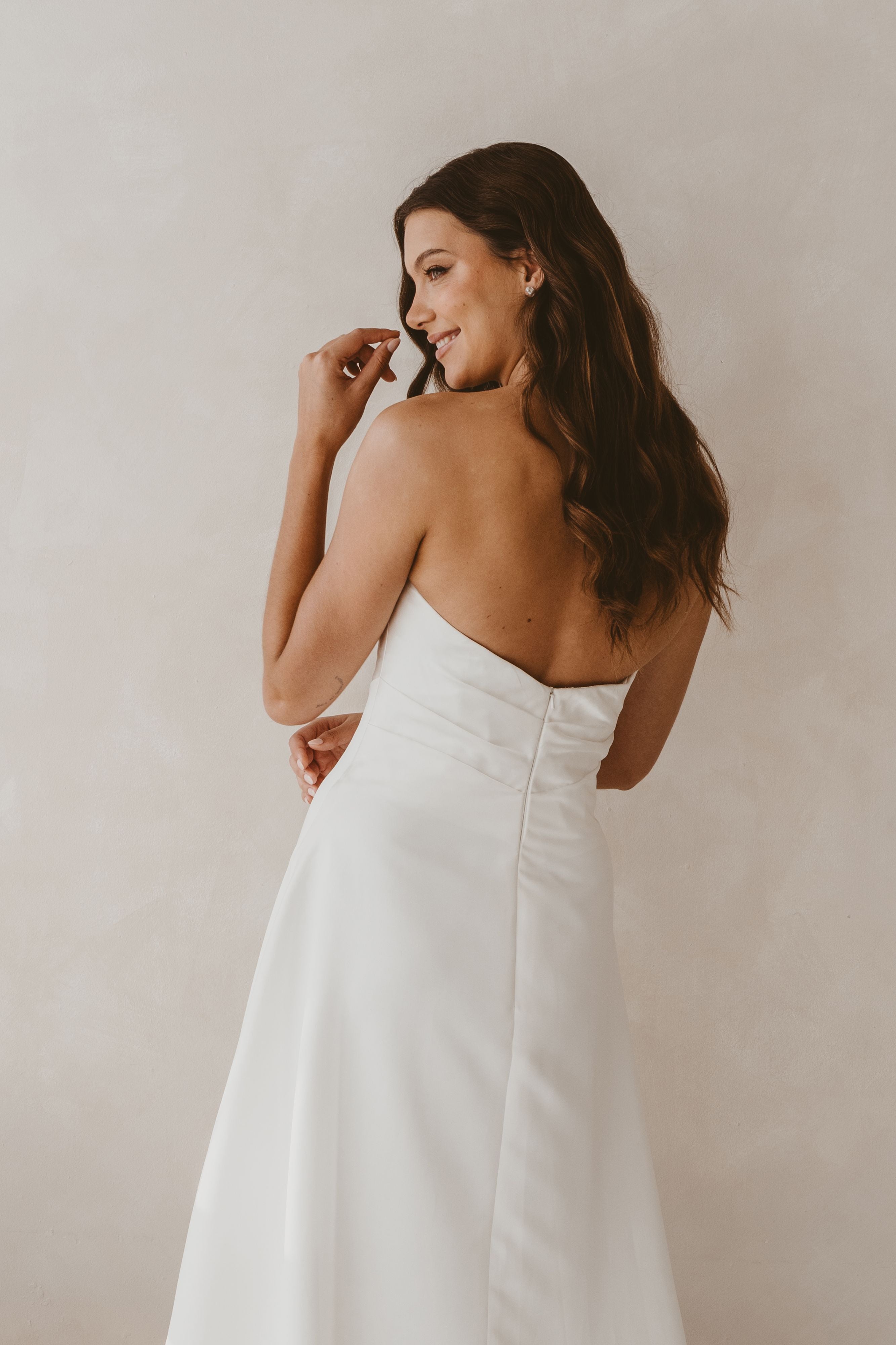 Woman wearing a white strapless dress against a plain background
