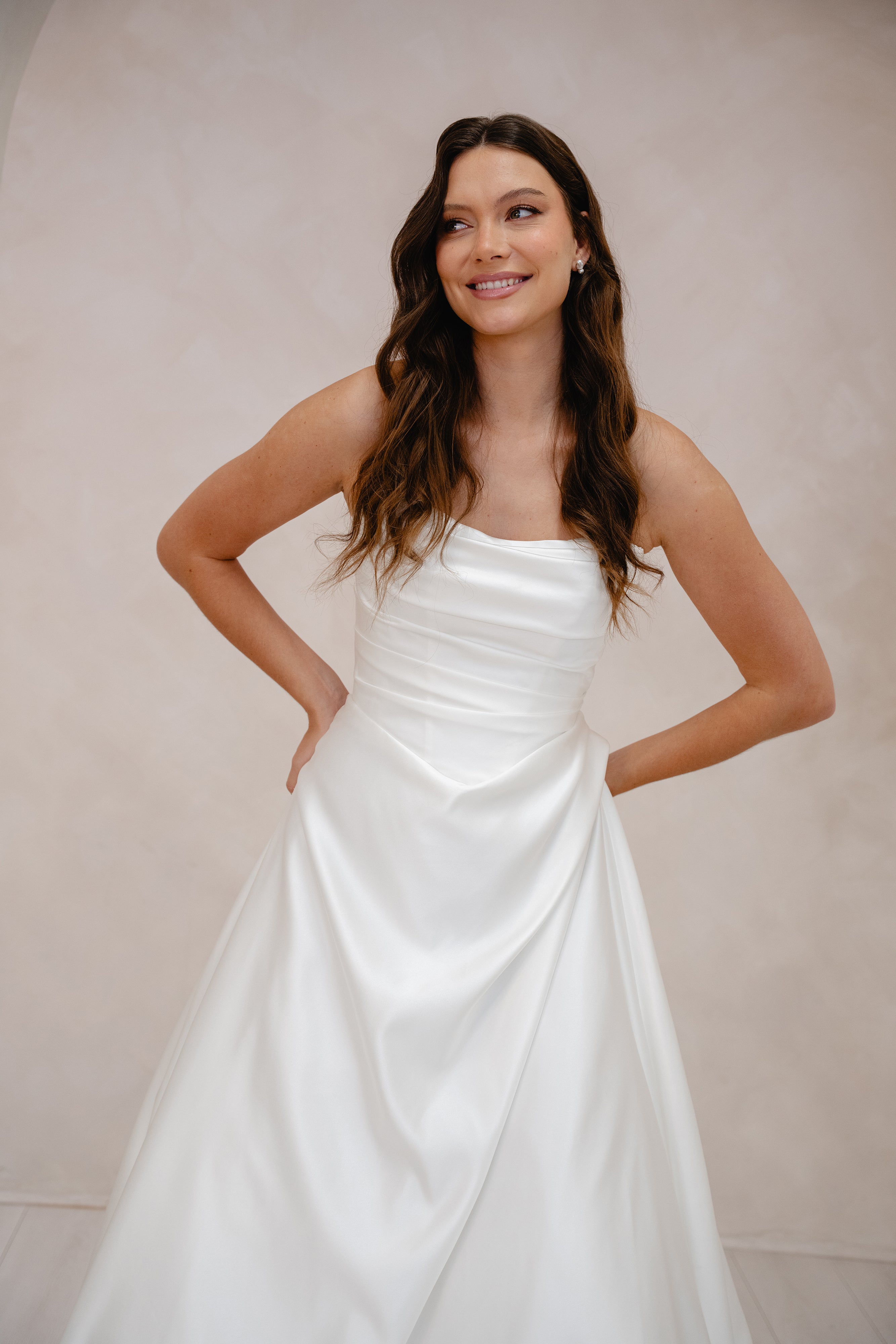 Woman wearing a white strapless dress against a plain background