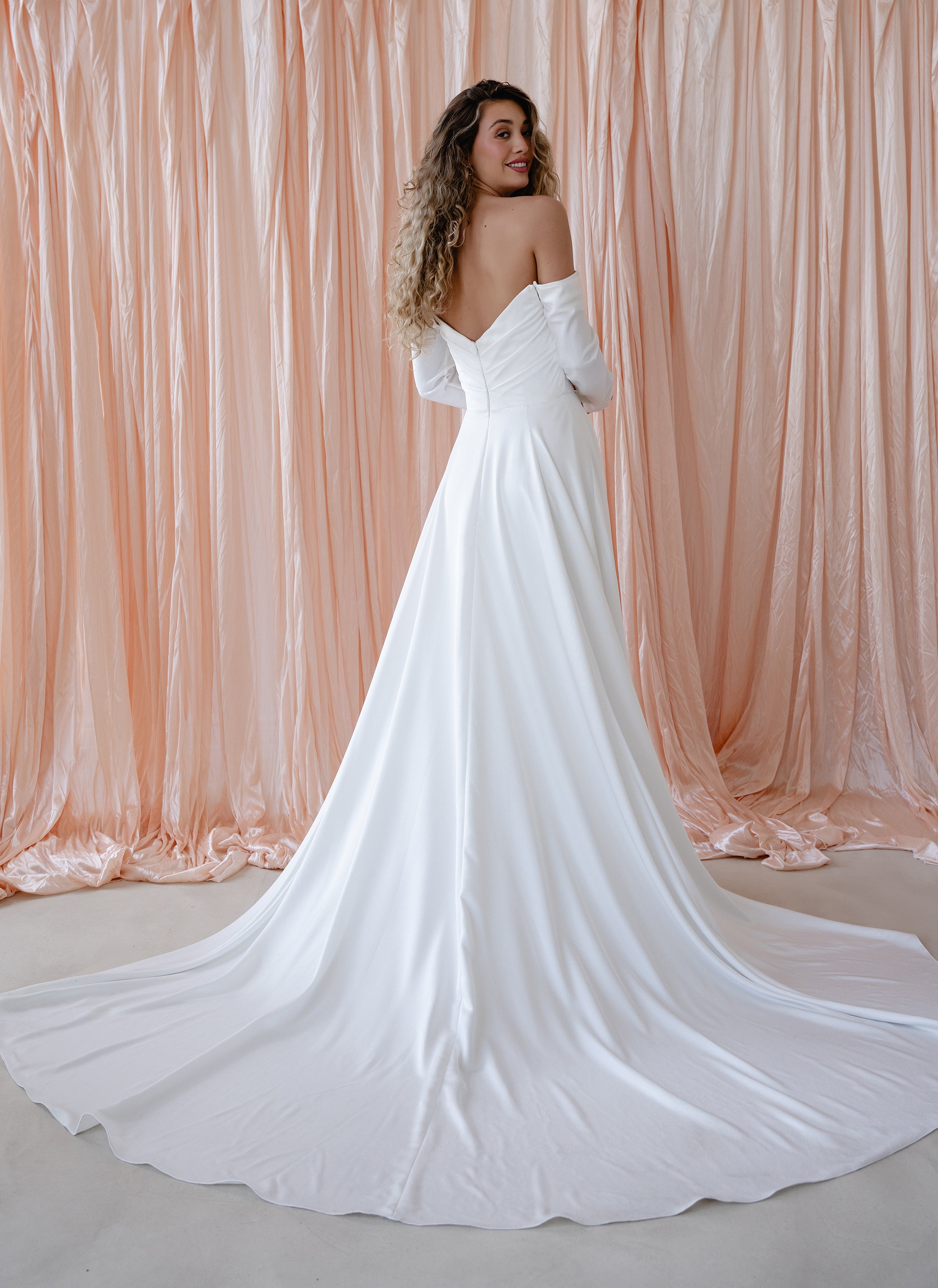 Bride wearing the River satin wedding dress with off-the-shoulder neckline and detachable sleeves.