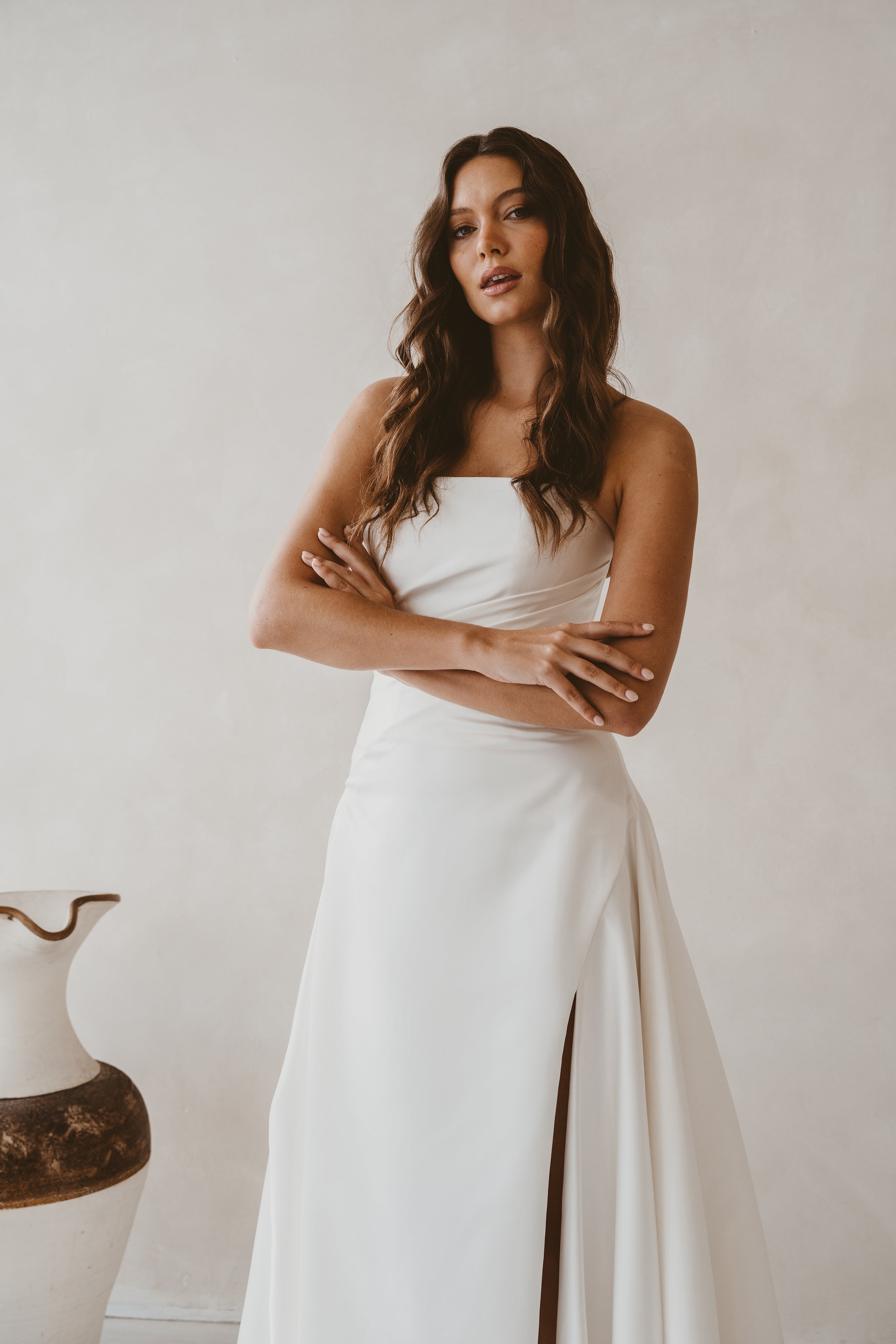 Woman in a white dress standing against a plain background