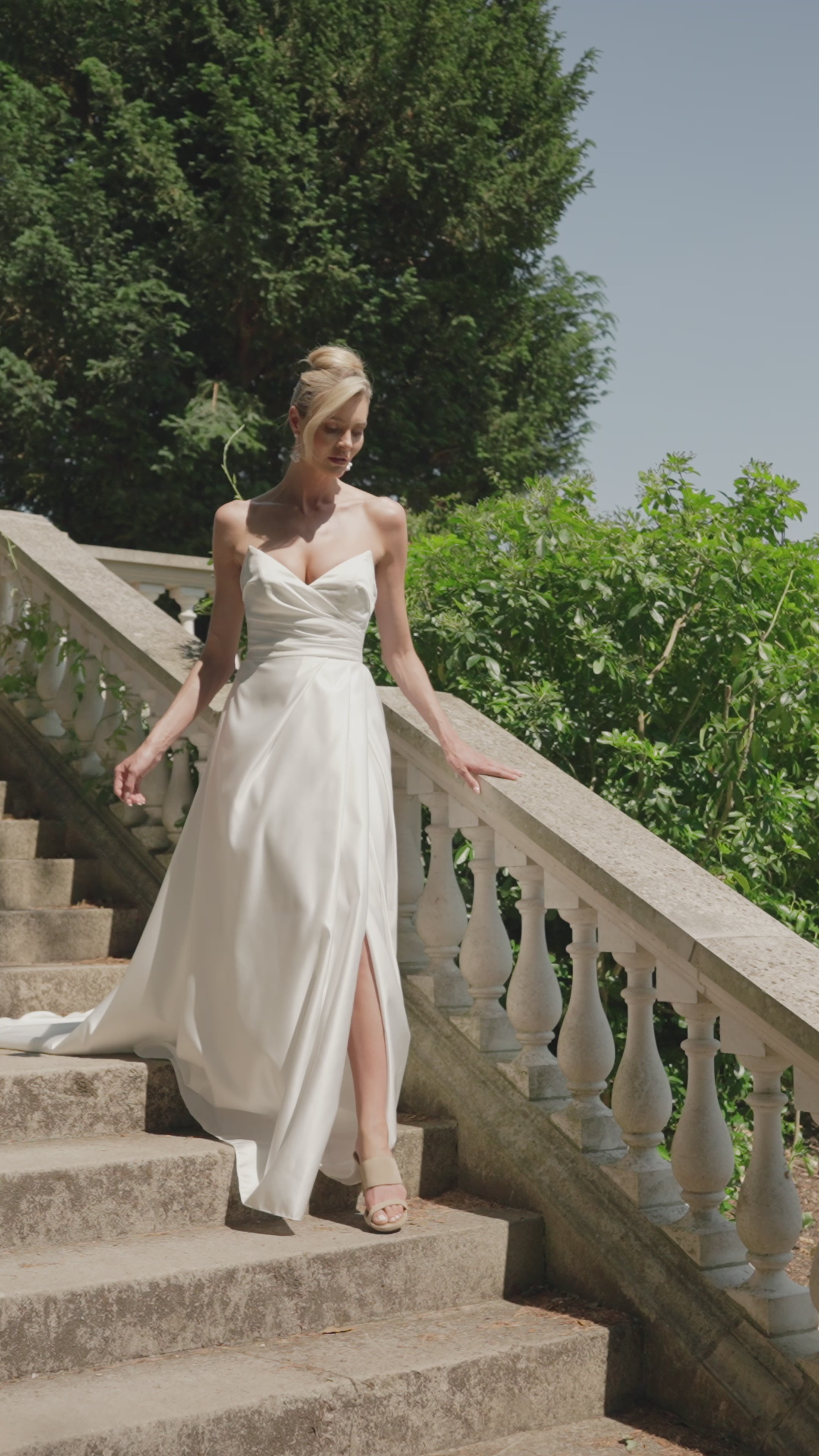 Women in strapless satin wedding dress moving around a beautiful garden