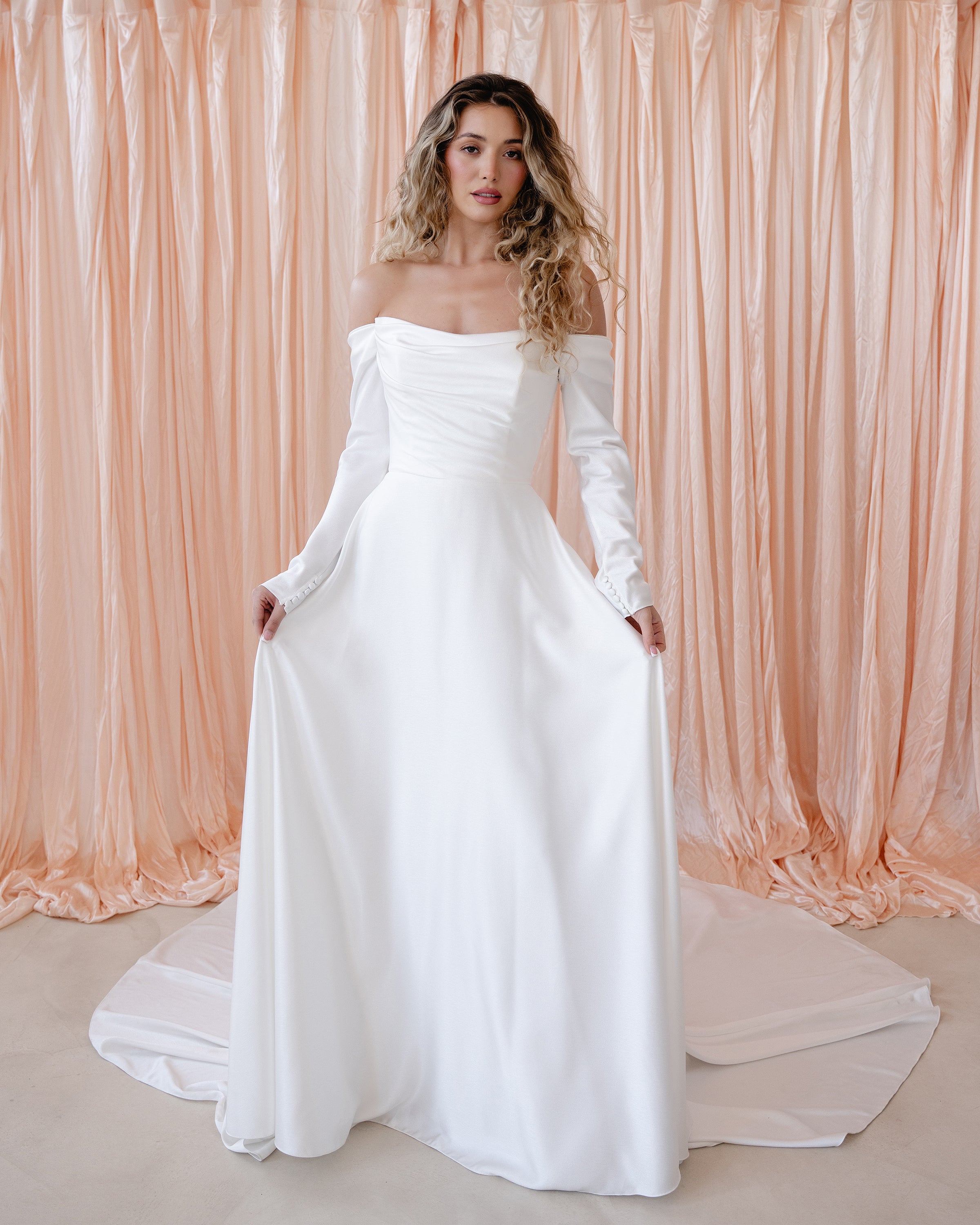 Bride wearing the River satin wedding dress with off-the-shoulder neckline and detachable sleeves.