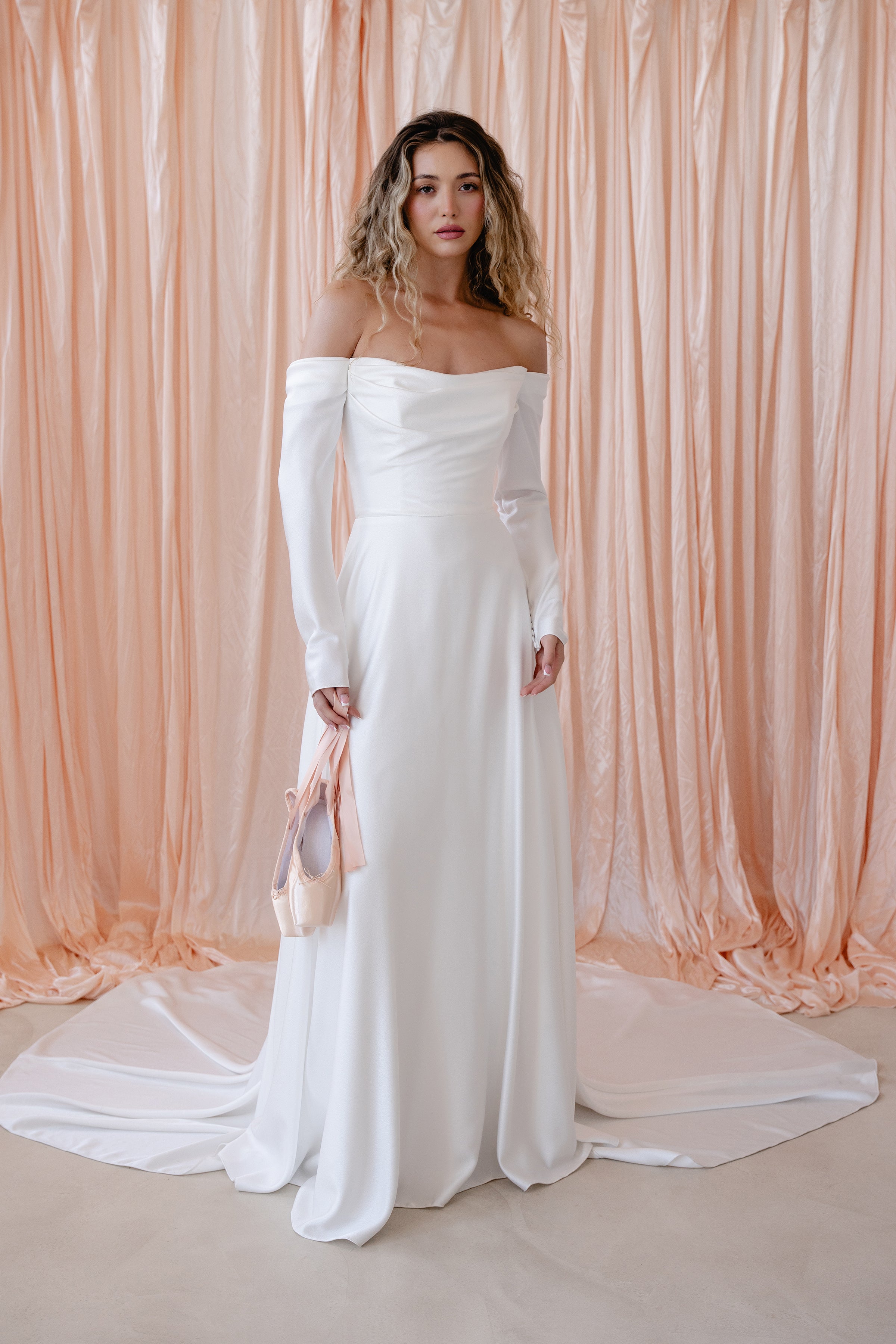 Bride wearing the River satin wedding dress with off-the-shoulder neckline and detachable sleeves.