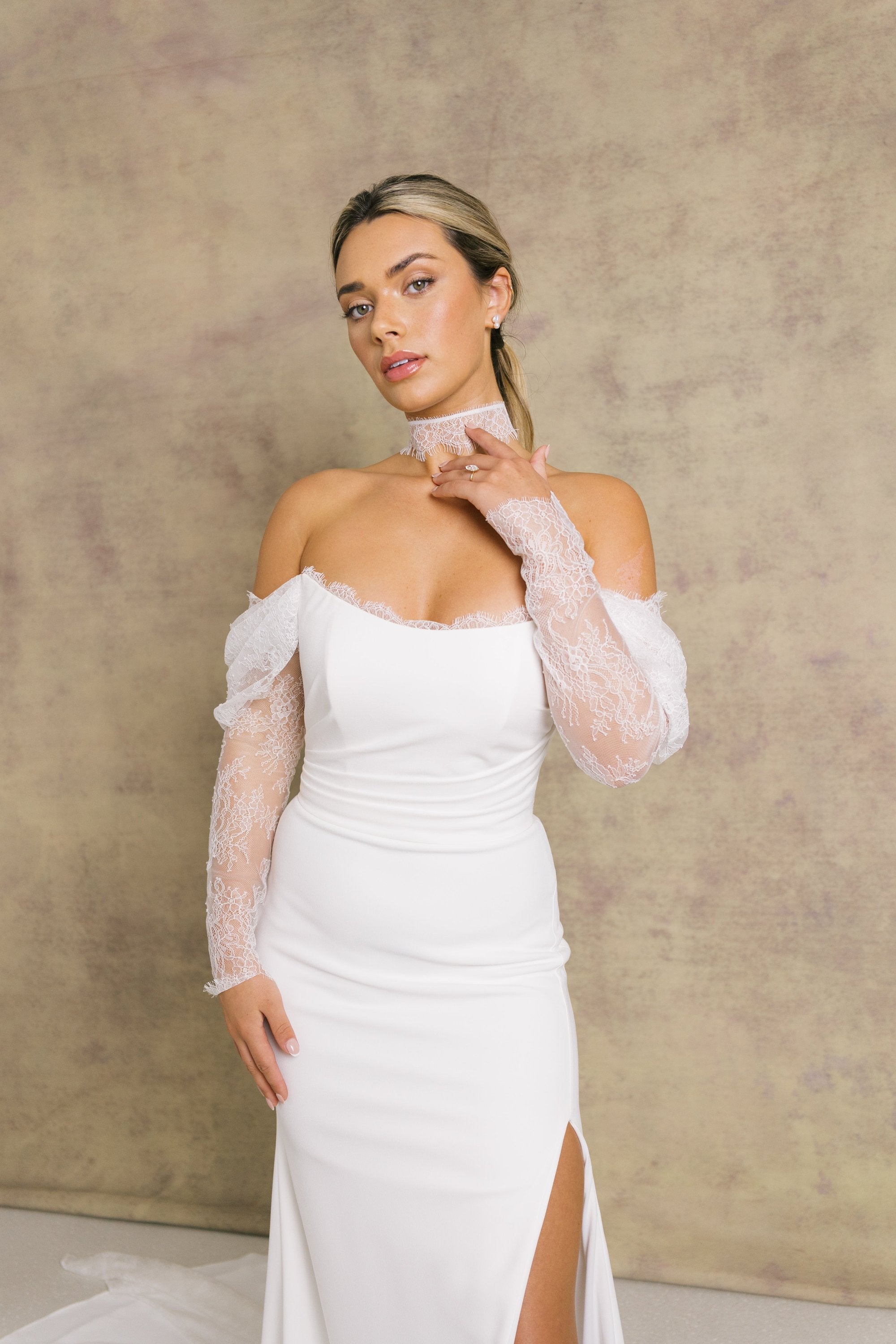 A woman in an elegant ivory strapless wedding dress with chantilly lace sleeves and a corseted bodice.