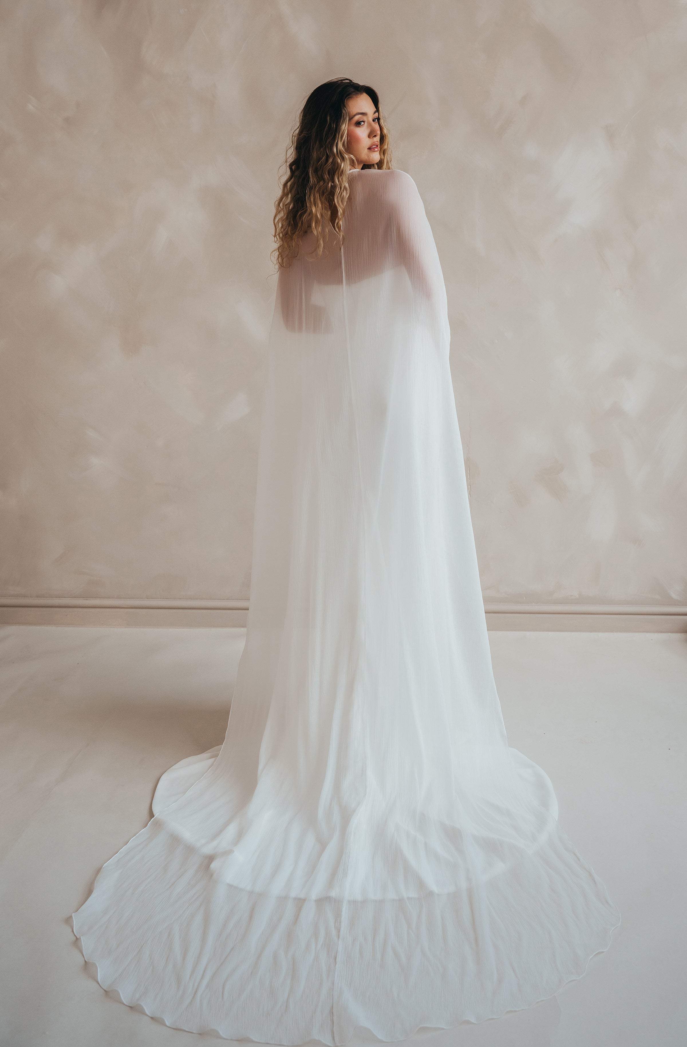 Bride wearing the Roxie chiffon bridal cape with flowing fabric and soft movement.