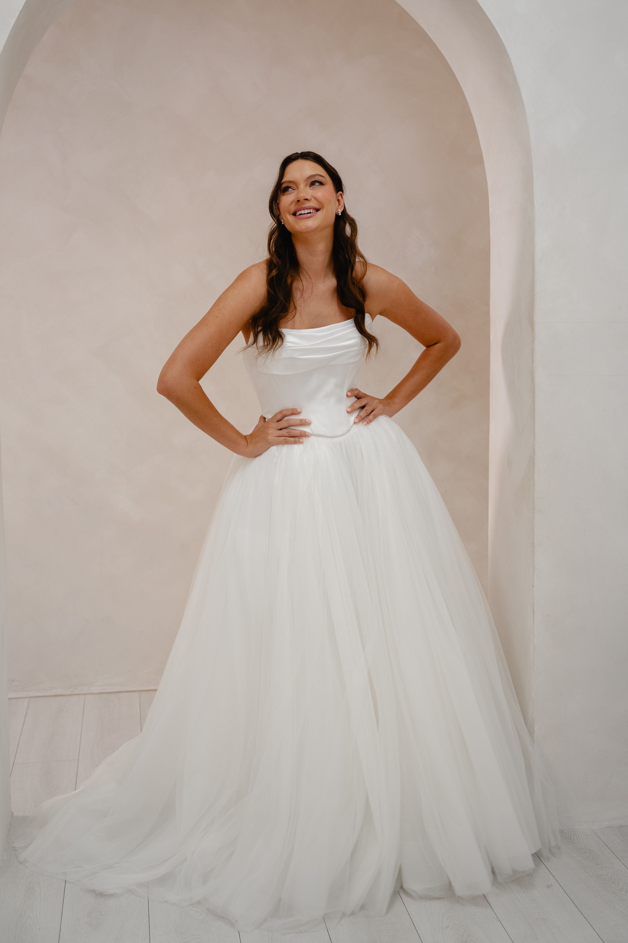 Woman in a white wedding dress standing in front of an archway.