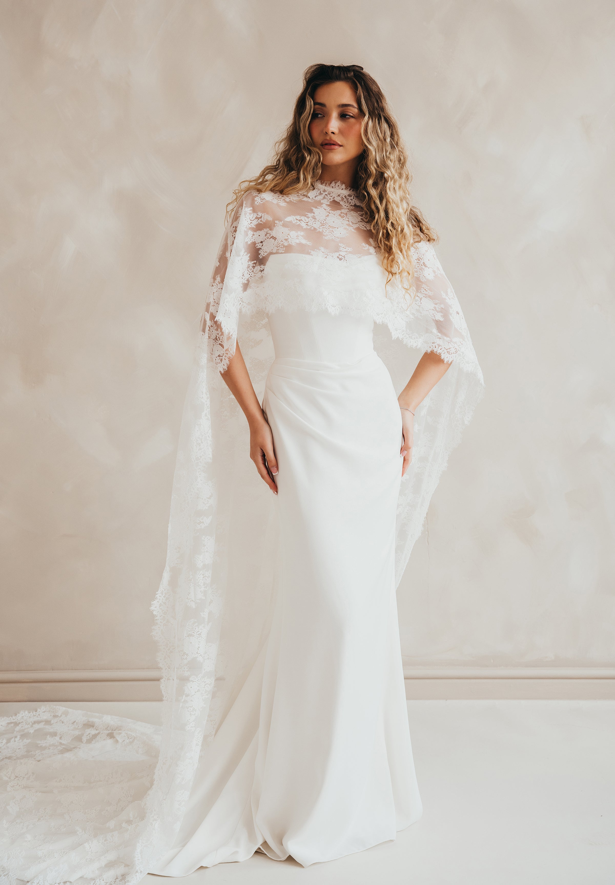Bride wearing the Lace Roxie bridal cape with high neckline and intricate lace detail.