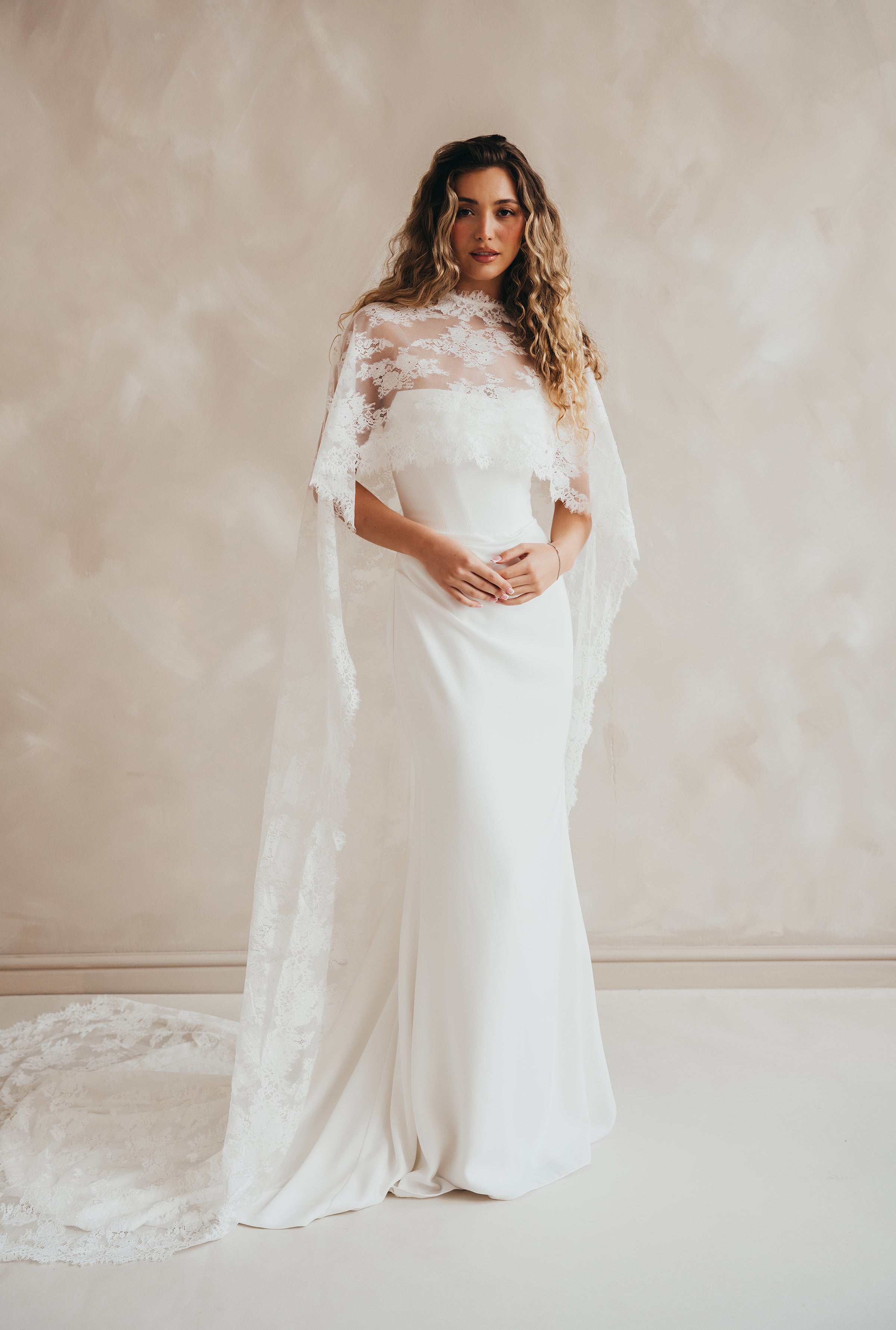 Bride wearing the Lace Roxie bridal cape with high neckline and intricate lace detail.