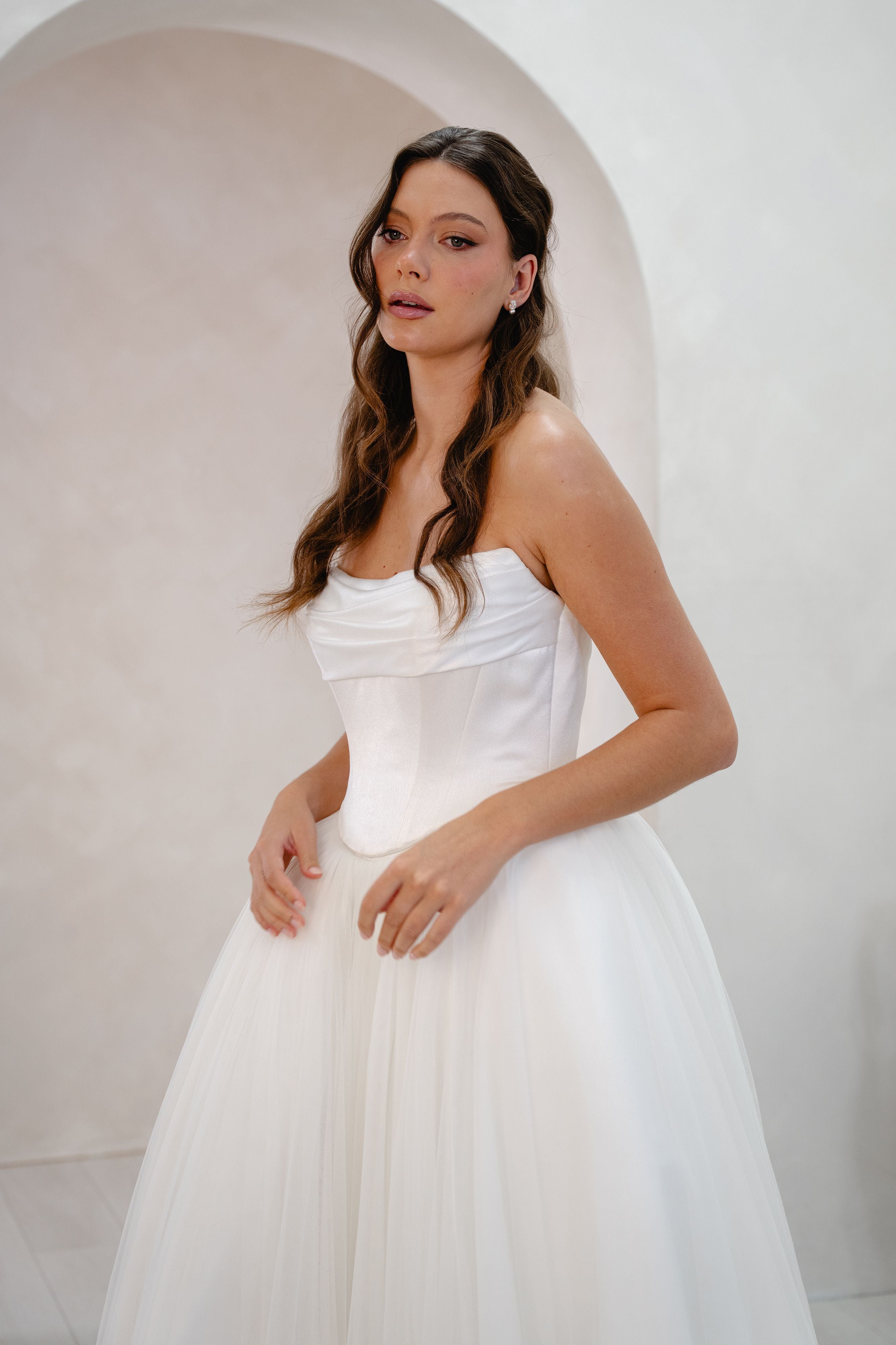 Woman wearing a strapless white wedding dress against a neutral background
