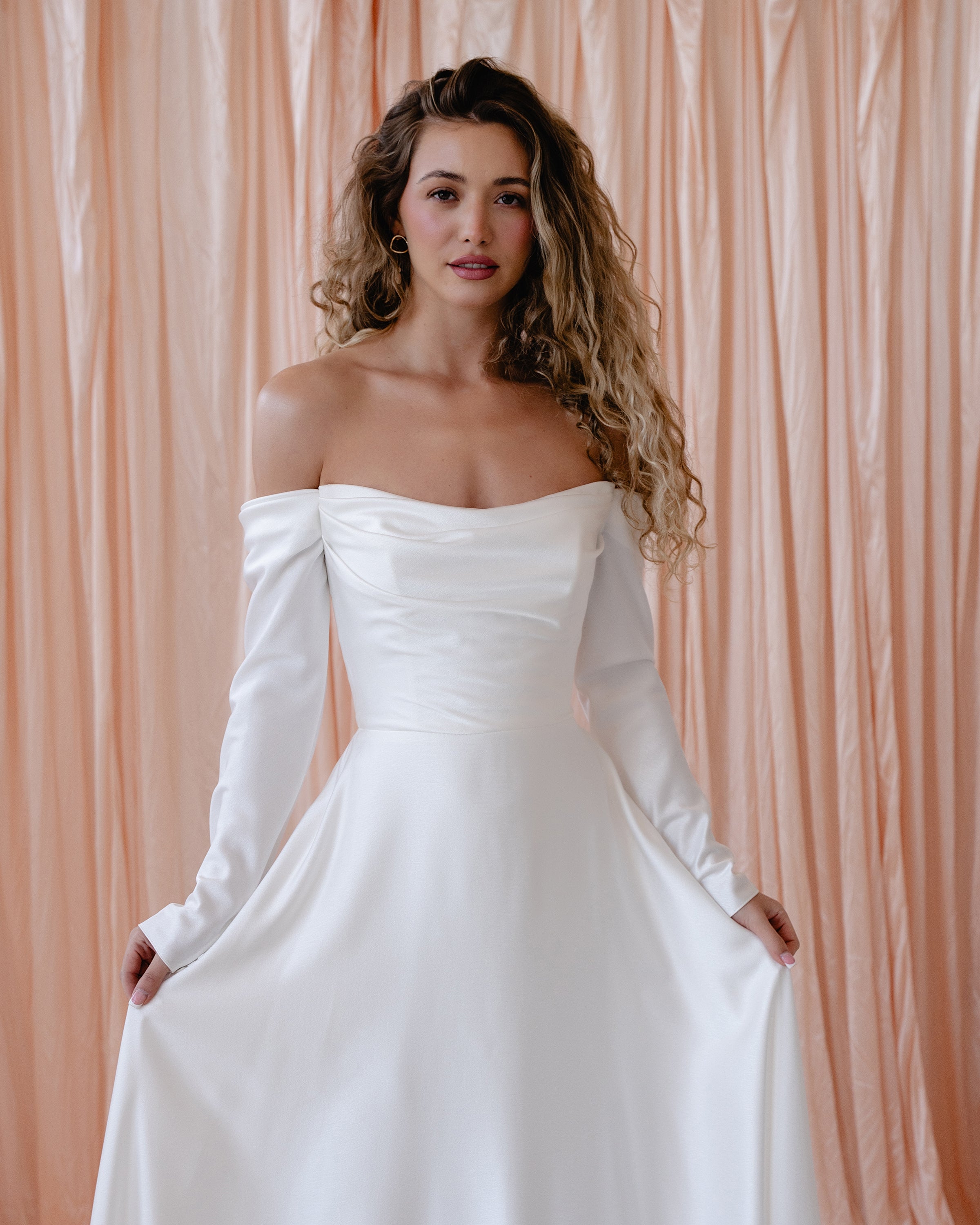 Bride wearing the River satin wedding dress with off-the-shoulder neckline and detachable sleeves.