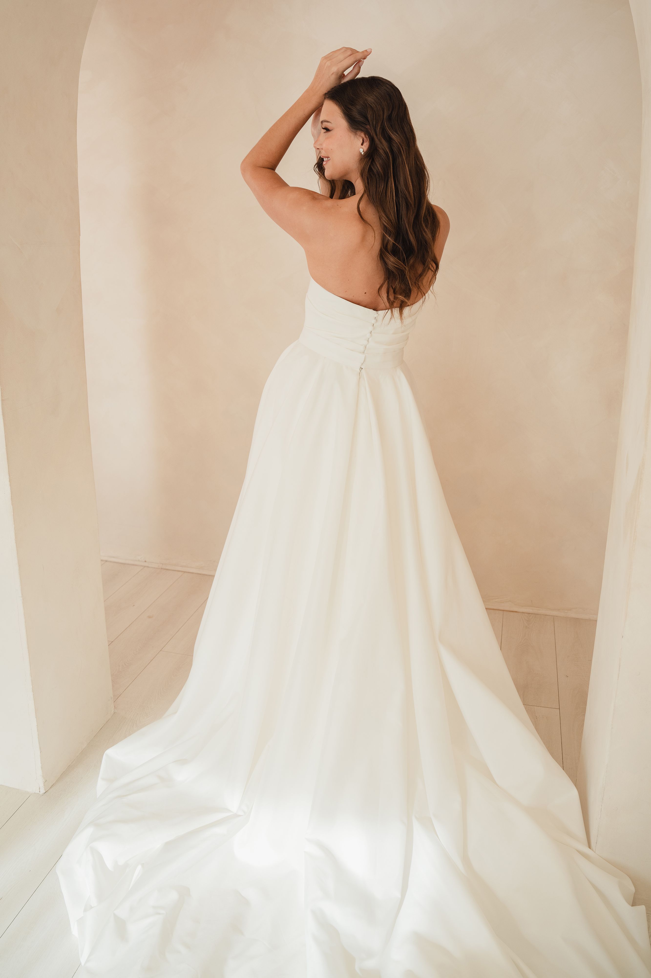 Woman in a white wedding dress standing against a neutral background