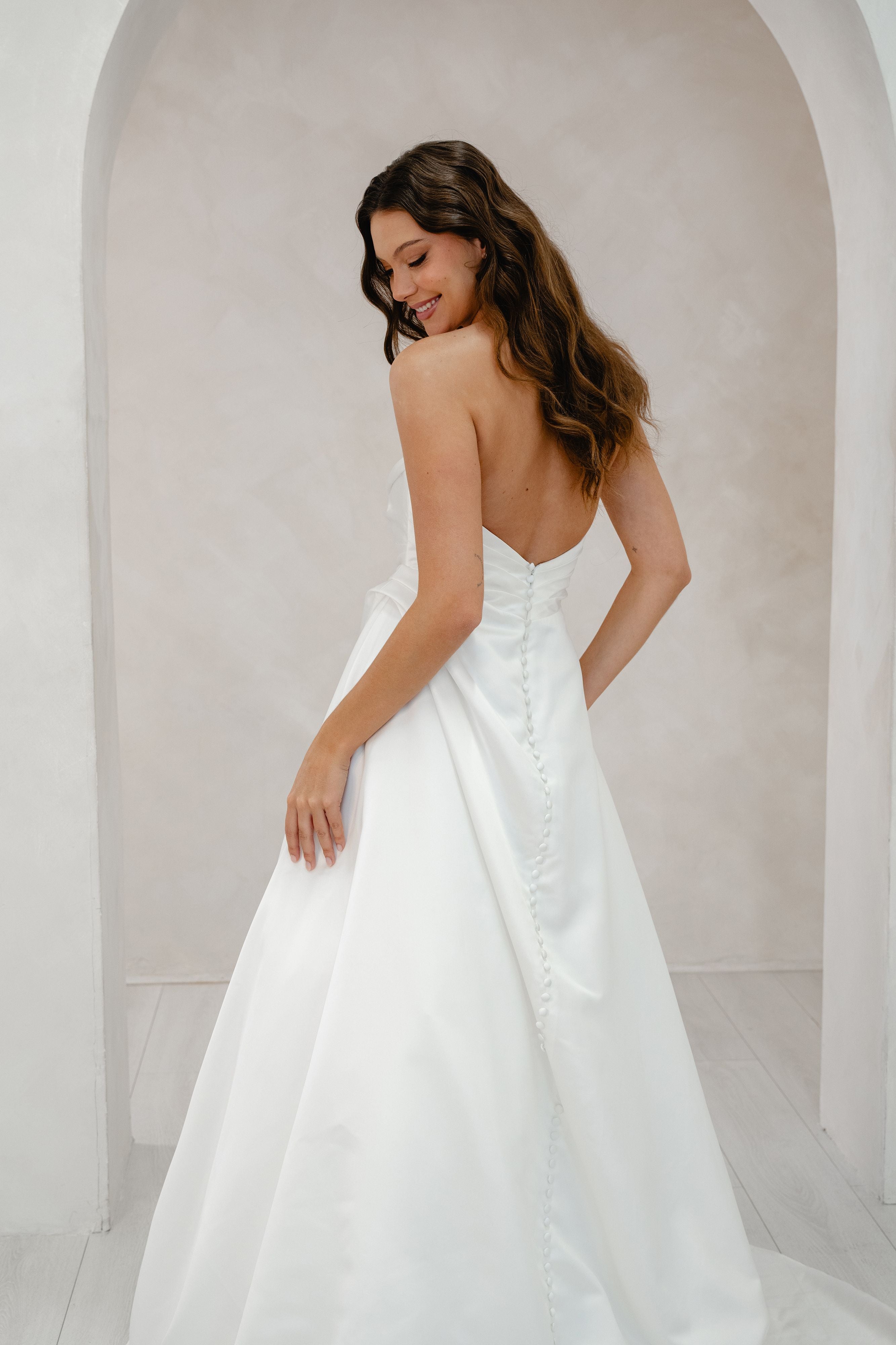 Woman wearing a white wedding dress with a flowing skirt in a neutral setting