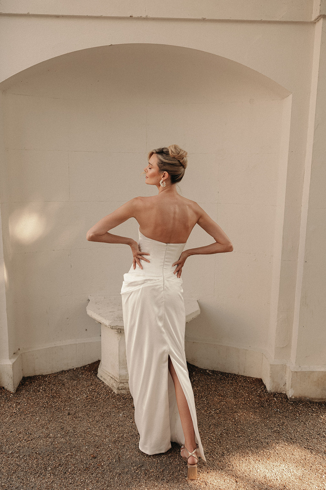 Woman in a ivory wedding dress with a low back and split in dress