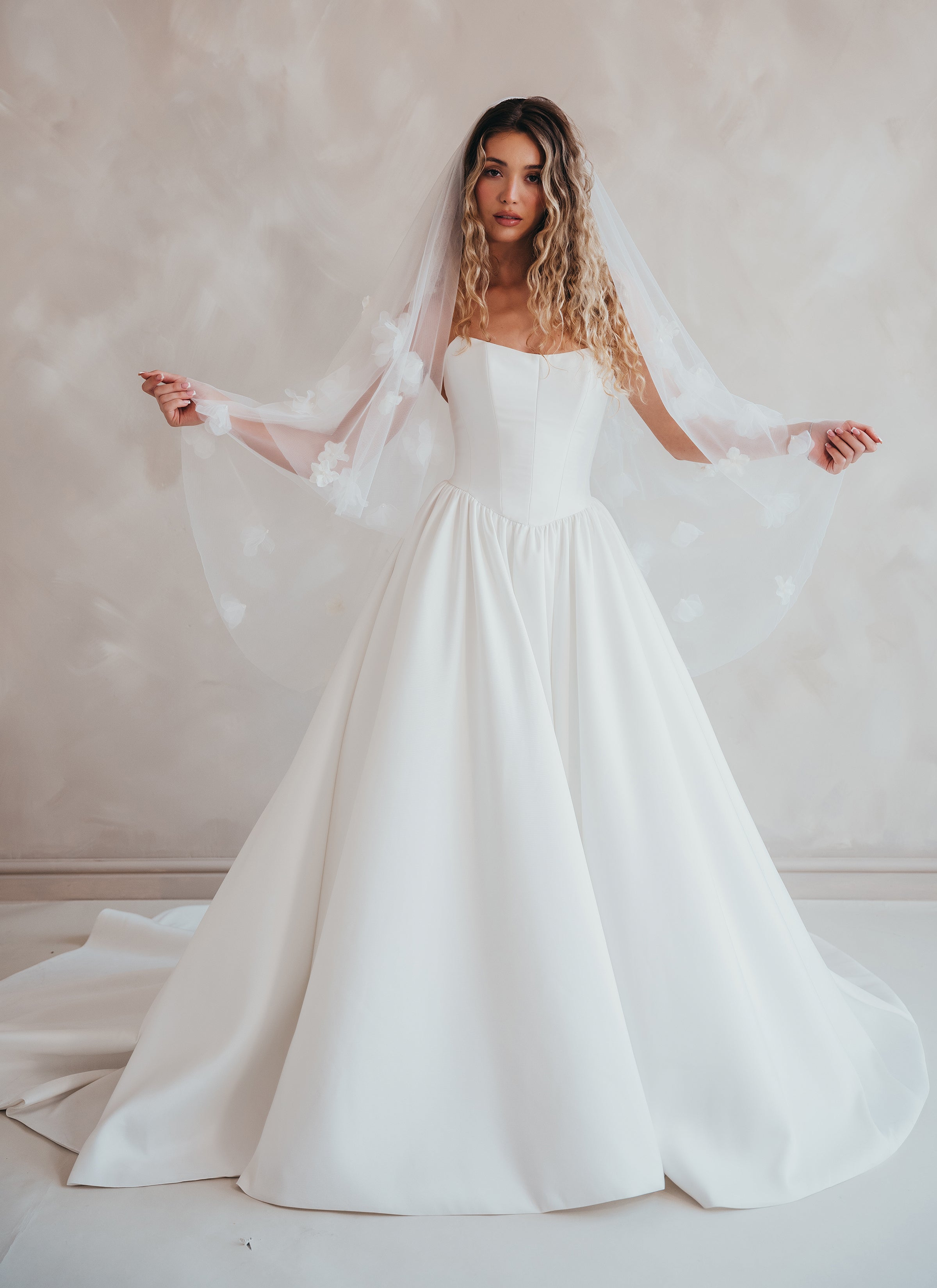 Bride wearing the Lua strapless Mikado wedding dress with pleated A-line skirt and two tier veil