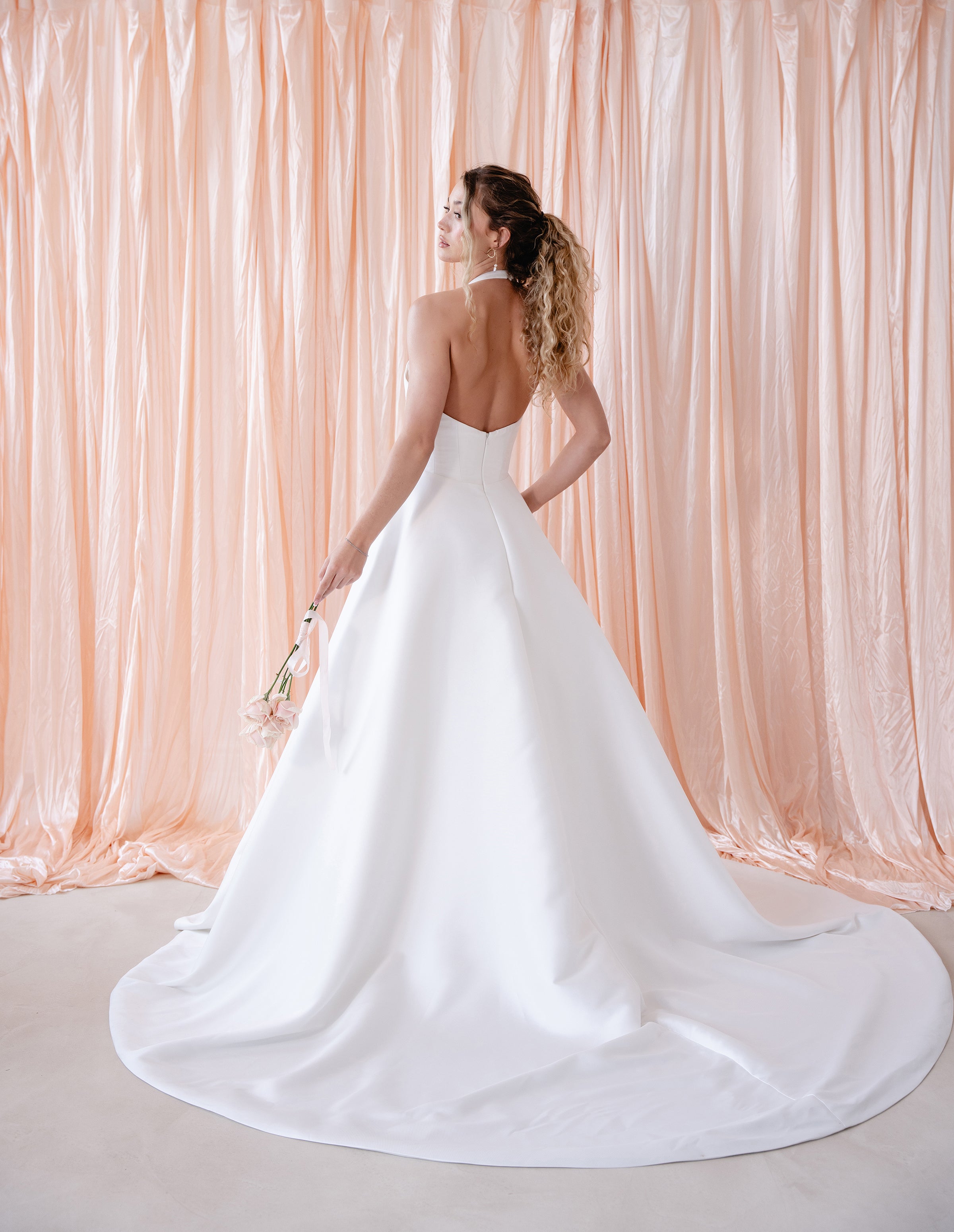 Bride wearing the Opal Mikado wedding dress with plunge halter neckline and A-line skirt.