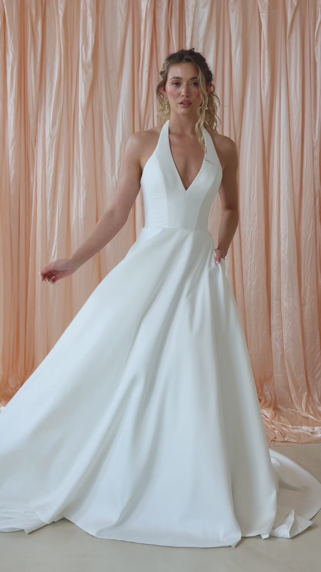 Bride wearing the Opal Mikado wedding dress with plunge halter neckline and A-line skirt.