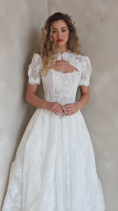 Bride wearing the Noemie Chantilly lace topper with puff sleeves and decorative lace trim.
