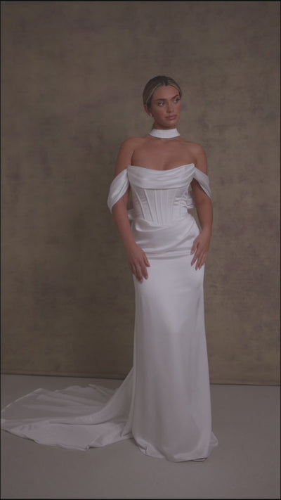 A woman in luxurious slipper satin wedding dress featuring a draped neckline on an exposed boned corset style drop waist bodice with draped bardot’s on our new ruched skirt.