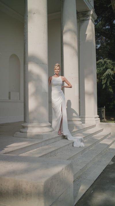 Woman in a ivory wedding dress moving on steps with classical columns in the background