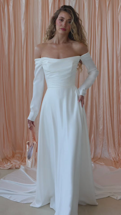 Bride wearing the River satin wedding dress with off-the-shoulder neckline and detachable sleeves.