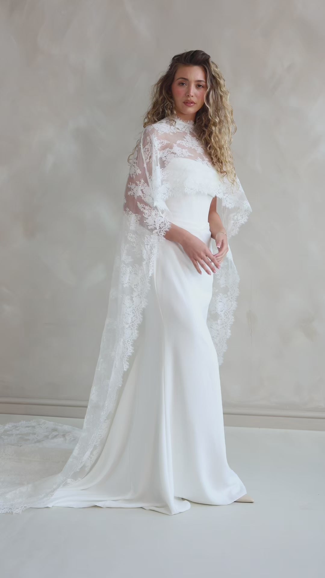 Bride wearing the Lace Roxie bridal cape with high neckline and intricate lace detail.