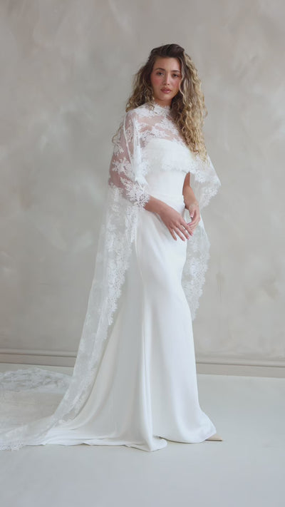 Bride wearing the Lace Roxie bridal cape with high neckline and intricate lace detail.