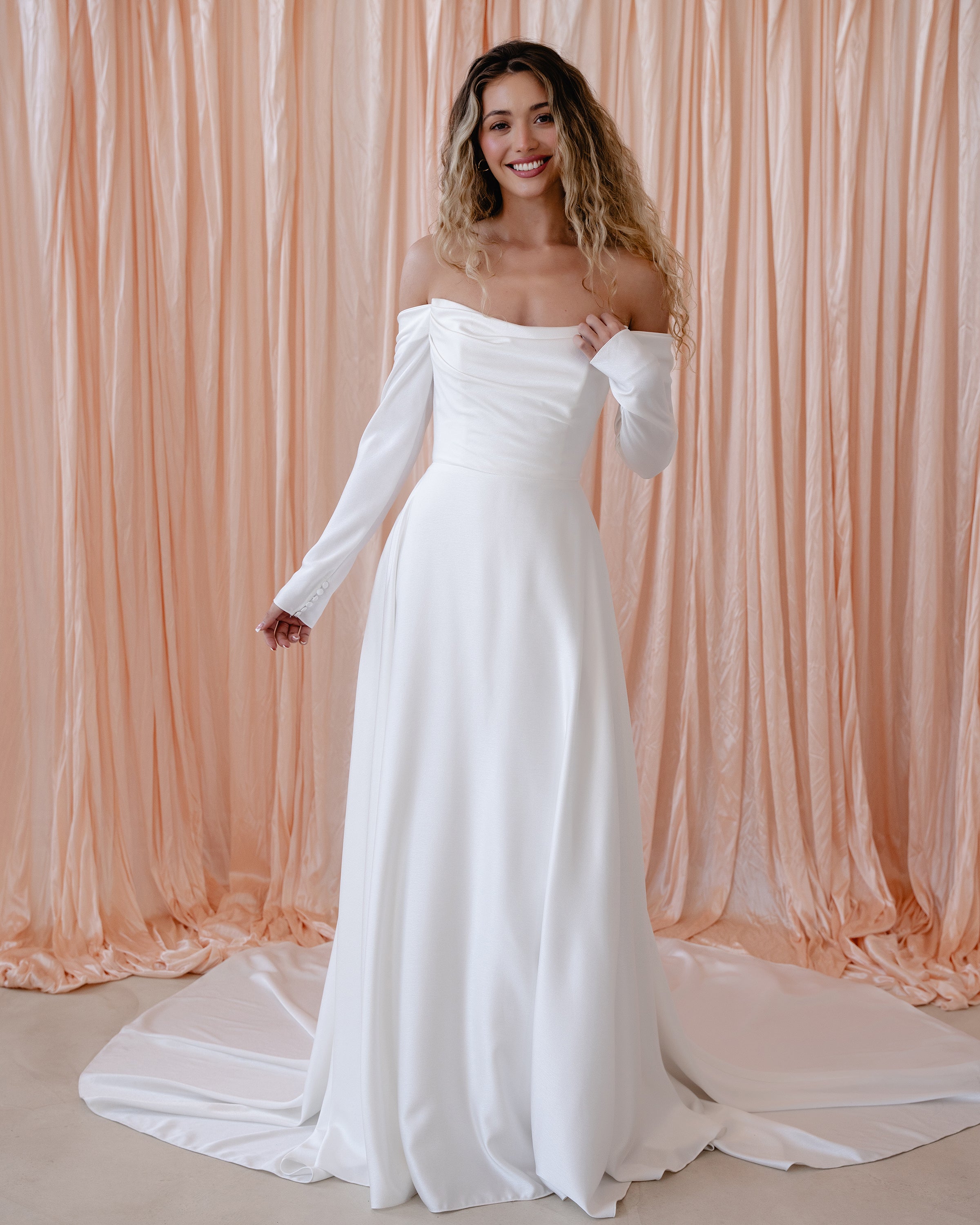 Bride wearing the River satin wedding dress with off-the-shoulder neckline and detachable sleeves.