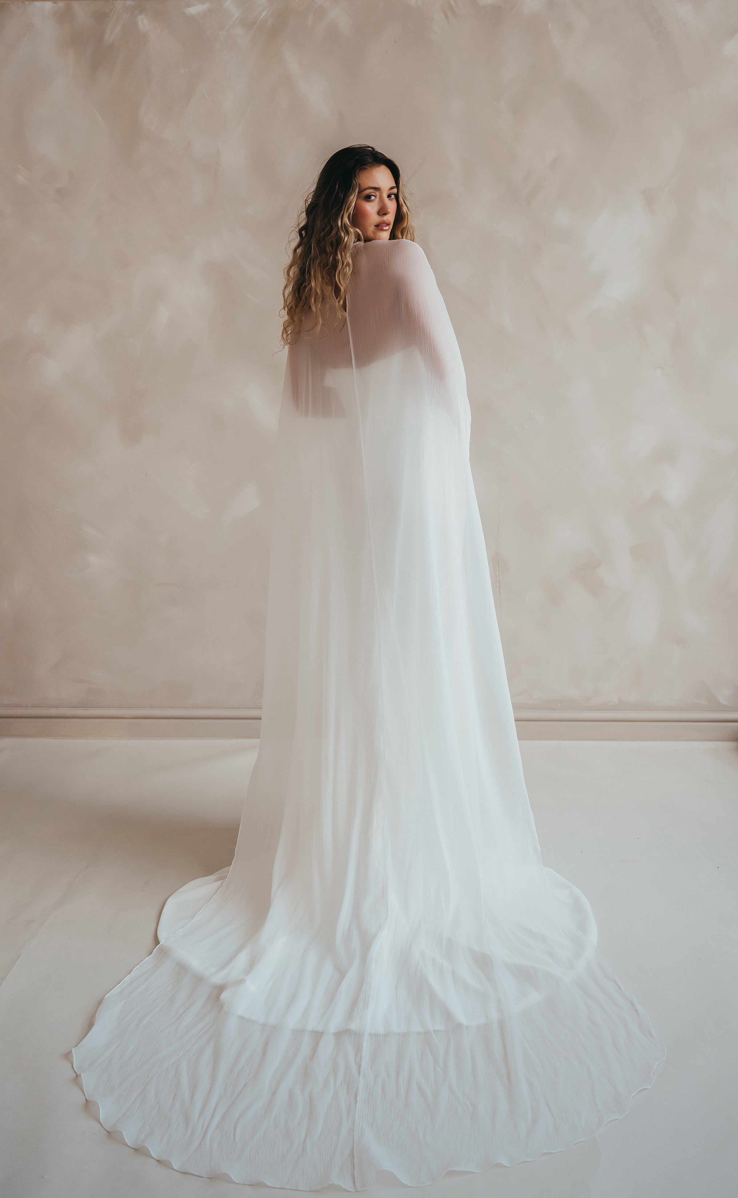 Bride wearing the Roxie chiffon bridal cape with flowing fabric and soft movement.
