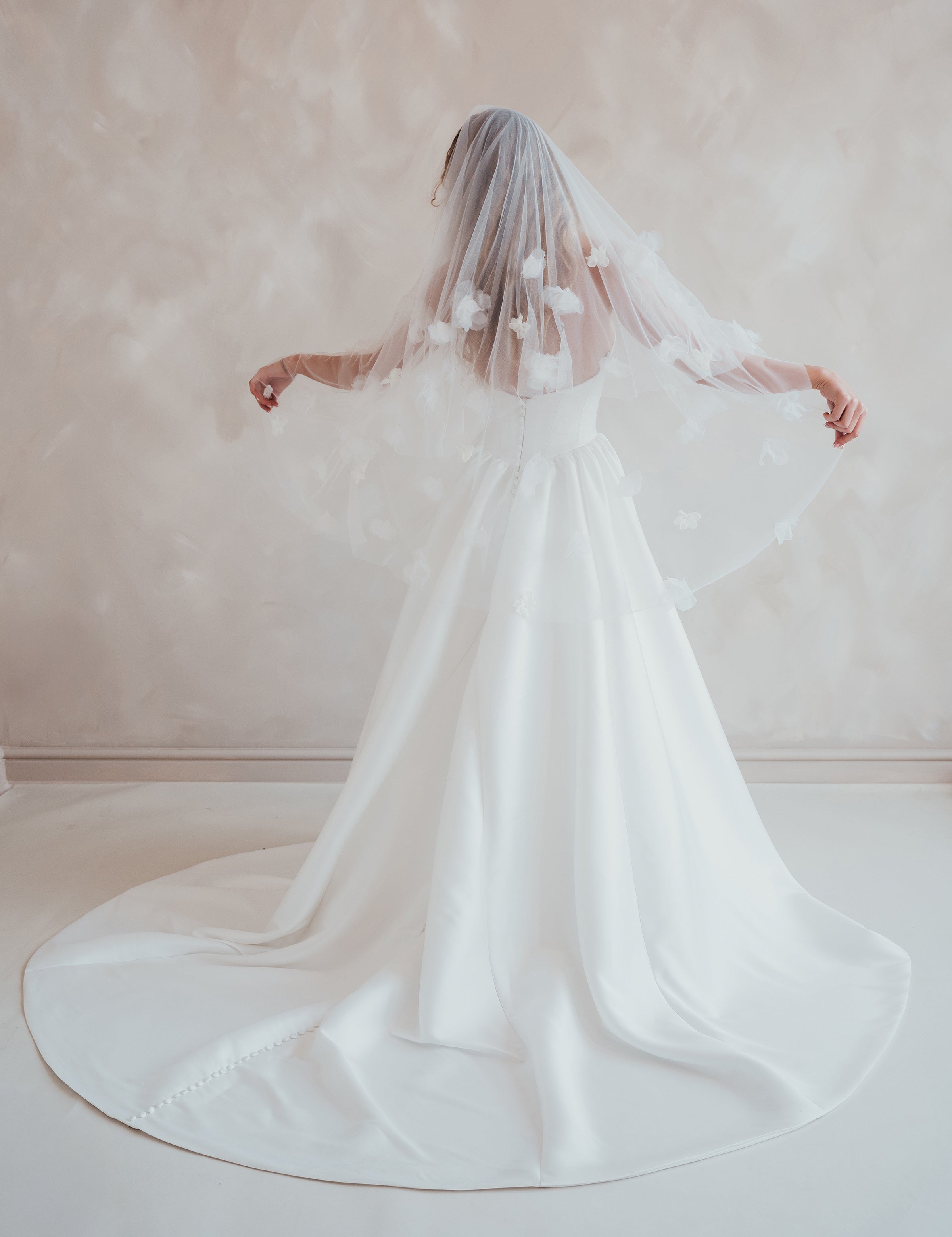 Bride wearing the Lua strapless Mikado wedding dress with pleated A-line skirt and floral wedding veil
