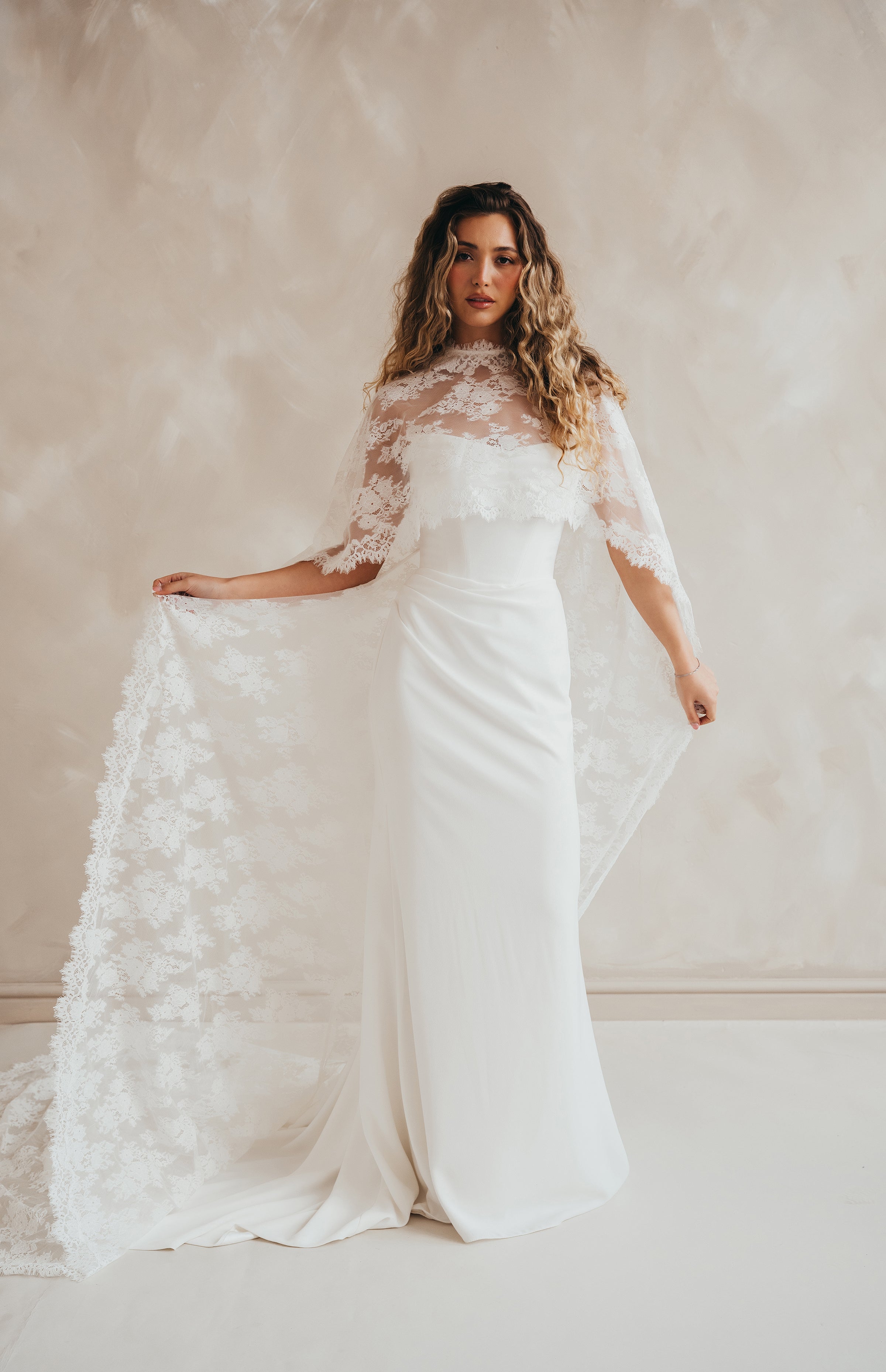 Bride wearing the Lace Roxie bridal cape with high neckline and intricate lace detail.